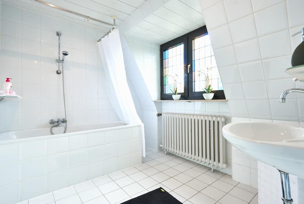 4-Raum-Appartement App073 Bad Waschbecken Mosaikfenster Badewanne Dusche weiße Fliesen