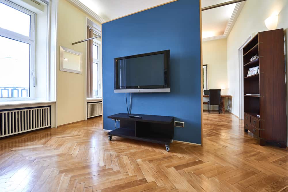 3-Raum-Appartement App501 Wohnbereich blauer Wandtrenner TV Kommode Schrank Parkett