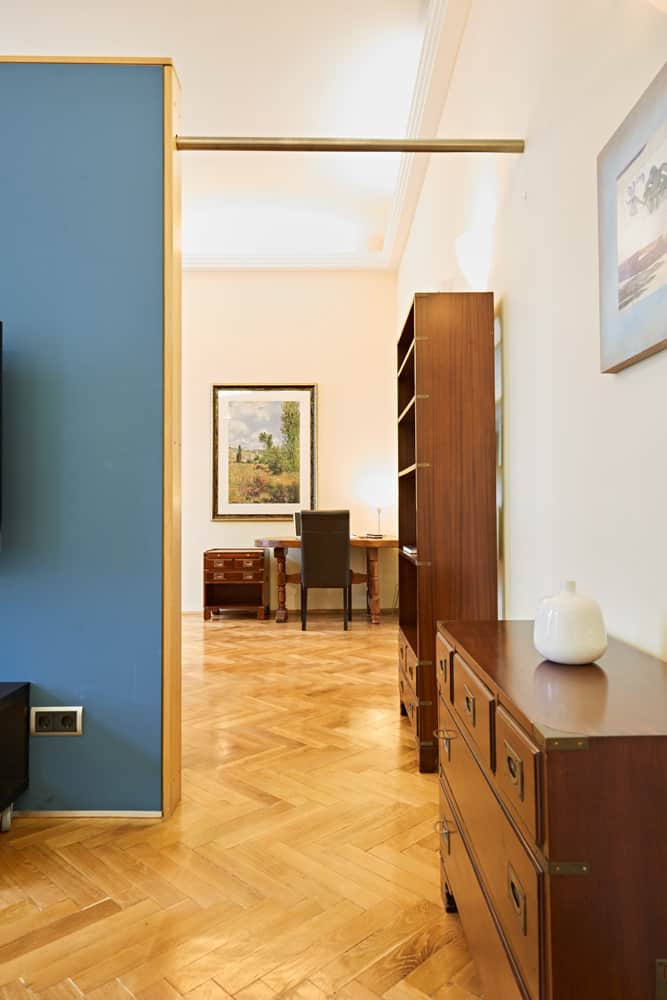 3-Raum-Appartement App501 Wohnbereich Kommode Schrank blauer Wandtrenner Schreibtisch Parkett