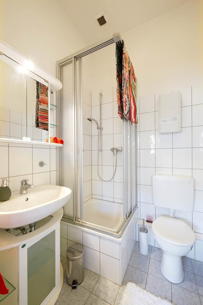 1-Raum-Appartement App524 Bad Dusche WC Waschbecken Spiegel Schrank weiße Fliesen