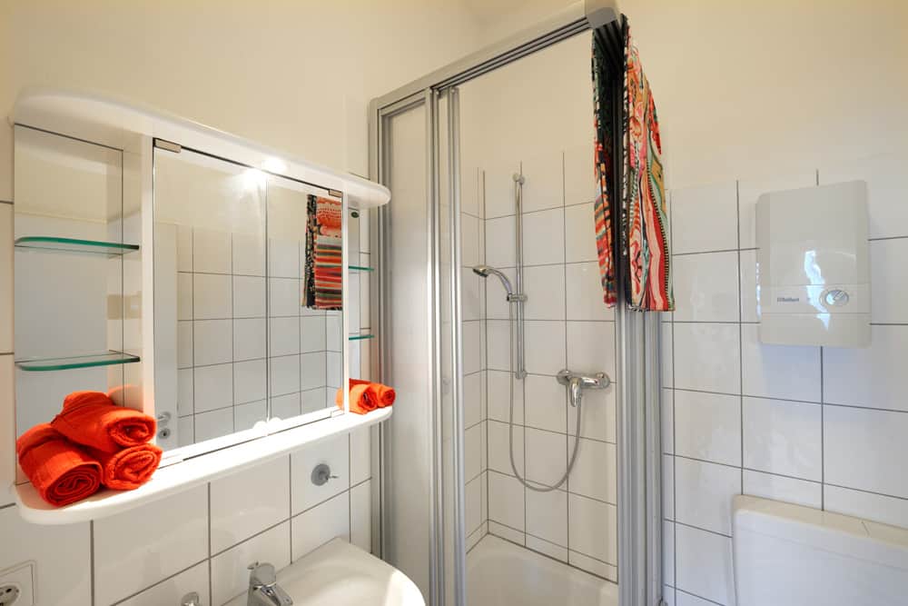 1-Raum-Appartement App524 Bad Dusche Waschbecken Spiegel Regal weiße Fliesen
