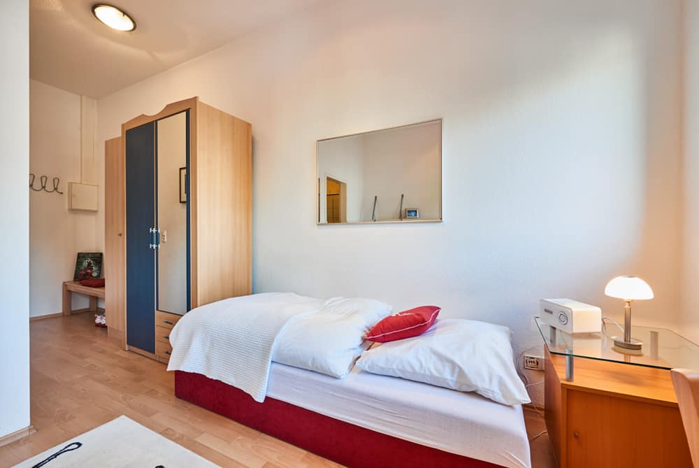 1-Raum-Appartement App524 Schlafbereich Bett Schrank Spiegel Nachttisch Sitzecke Laminat
